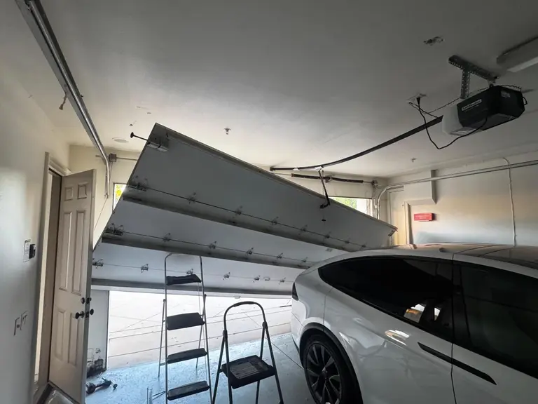 Garage door hanging dangerously off its track inside a Los Angeles garage before emergency repair by MSB