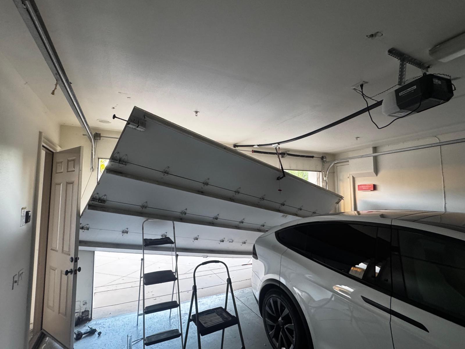 Garage door hanging dangerously off its track inside a Los Angeles garage, track repair and realignment needed